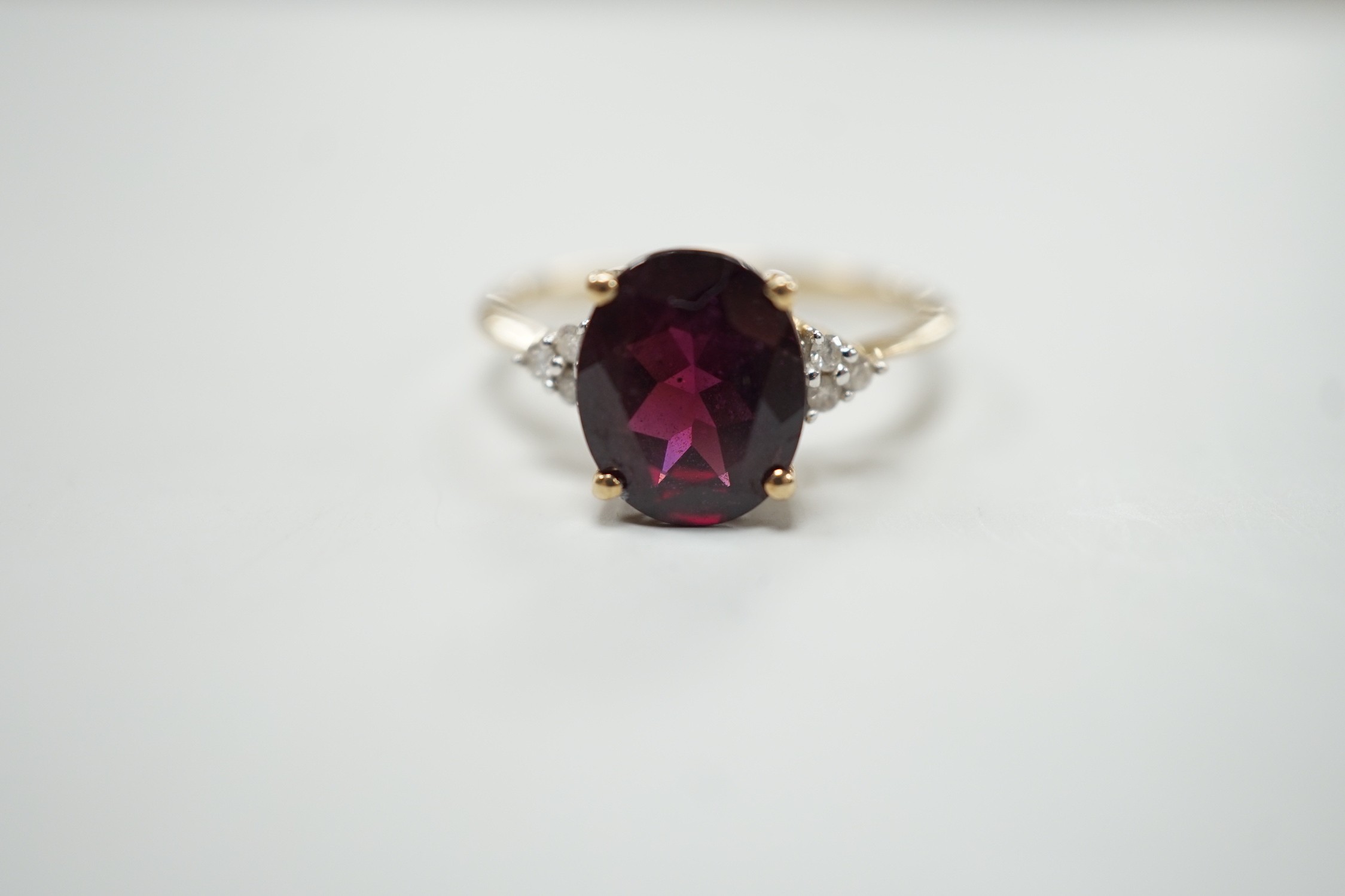 A modern 9ct gold, single stone oval cut garnet and six stone diamond chip set dress ring, size R/S, gross weight 2.8 grams.